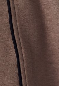 Brown fabric with a smooth texture, featuring a black seam accent on one side for detail. The fabric shows slight stretch and flexibility.