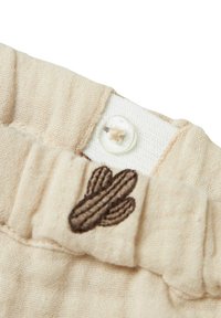 Tissu en lin beige avec une taille froncée, fermée par un bouton-pression blanc et un design de cactus brodé en marron.