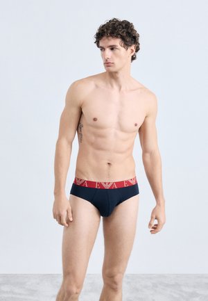 Roupa interior preta com cintura elástica vermelha com logótipo, ajuste justo, feita em tecido macio, com design clássico de cueca. Sem padrões adicionais.