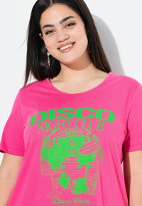 Felroze t-shirt met een losse pasvorm, voorzien van een groene grafische afbeelding van een discobal en tekst in vetgedrukte letters met de tekst "DISCO NIGHT CLUB".