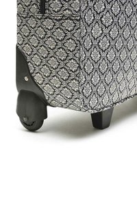 Rolling suitcase with a black and white floral pattern, durable fabric, hard plastic corners, and four sturdy wheels for easy mobility.