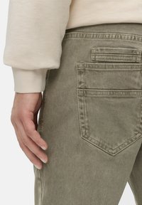 Lys grønne denimjeans med baglomme med en vandret søm og en tekstureret overflade, parret med en lys langærmet top.