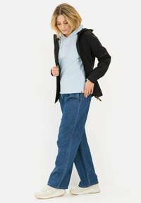 Sort letvægtsjakke over en lys blå hoodie, parret med blå denimjeans og hvide sneakers. Glatte stoffer og afslappet pasform.