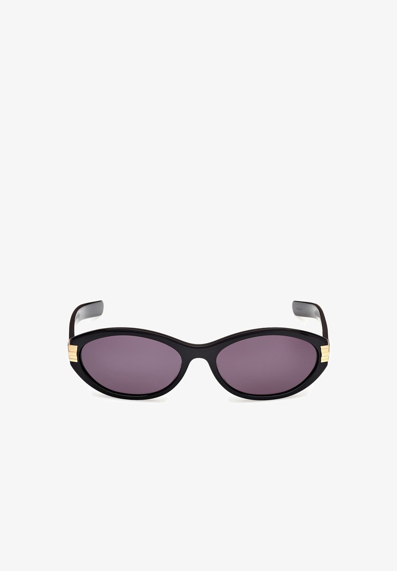 Zwarte cat-eye zonnebril met paarse lenzen. Kenmerkt gouden accenten bij de slapen. Glad kunststof frame met een glanzende afwerking.
