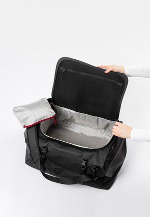 Borsa da viaggio nera con una grande apertura, interno foderato grigio e una tasca con zip. Include una pochette grigia staccabile con una zip rossa.