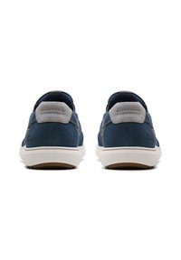 Marineblaue Slipper aus glattem Leder-Obermaterial, mit grauen Wildleder-Akzenten an den Fersen und einer weißen Gummisohle mit brauner Profilsohle.