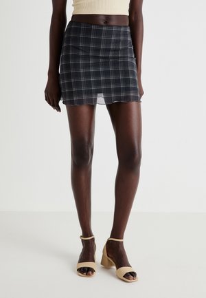 Jupe mini en tartan noir avec un ourlet festonné, fabriquée en tissu léger. Présente une silhouette ajustée et un éclat subtil.