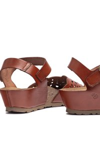 Brown leather wedge sandals with adjustable straps, perforated upper for breathability, and cork footbed. Textured rubber sole for grip.