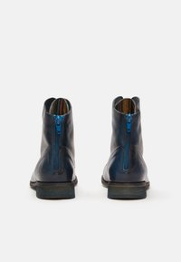 Botas de cuero azul marino hasta el tobillo con cremallera lateral, acabado texturizado y un forro interior de rayas multicolores, diseñadas con un tacón bajo.