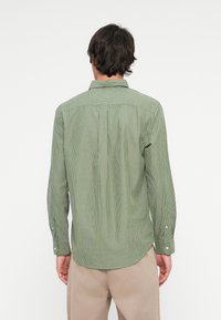 Groen gestreept shirt met een getailleerde pasvorm, voorzien van een button-down kraag, lange mouwen met knoopmanchetten en een gebogen zoom.