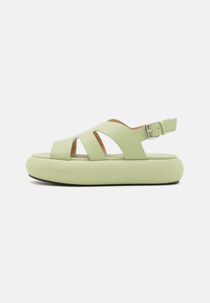 Light green sandals made of textured leather, featuring a thick sole, open toe design, and adjustable ankle strap with metal buckle.