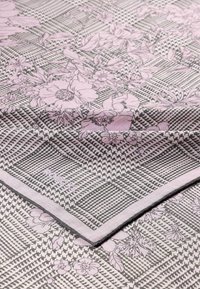 Floral-patterned fabric in pink and gray, featuring a houndstooth texture and a stitched edge. Includes subtle floral designs and branded detailing.