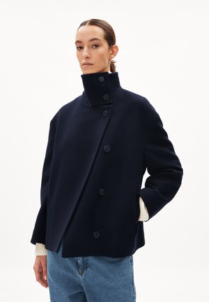 Navy-Wollmischungsjacke mit hohem Kragen, die an der Vorderseite über fünf Knöpfe verfügt und Seitentaschen hat. Lange Ärmel mit Rippbündchen.