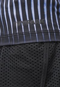 Top atlético negro con rayas verticales azules, de la marca "IVYPARK", combinado con pantalones cortos de tela perforada negros.