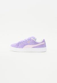 Violet suede-tossut valkoisilla kumipohjilla, joissa on vaaleanpunainen logo ja yksityiskohtia, pyöreä kärki ja perinteinen nauhakiristys.