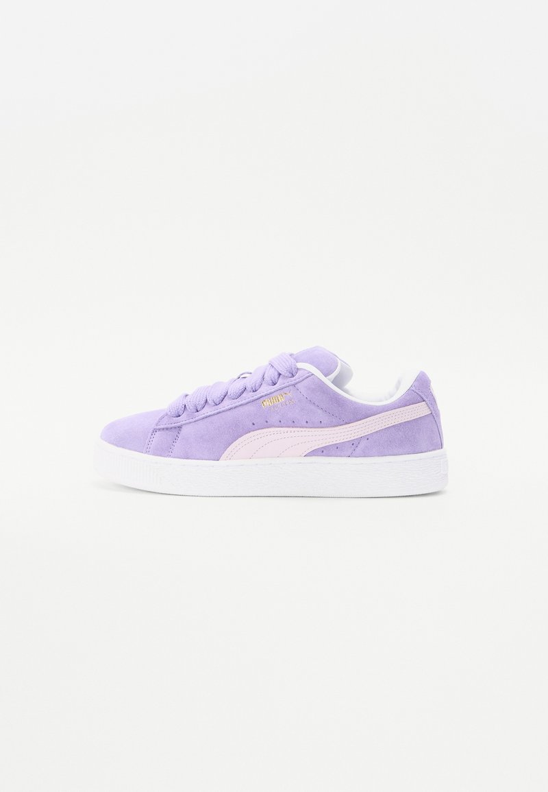 Violet suede-tossut valkoisilla kumipohjilla, joissa on vaaleanpunainen logo ja yksityiskohtia, pyöreä kärki ja perinteinen nauhakiristys.