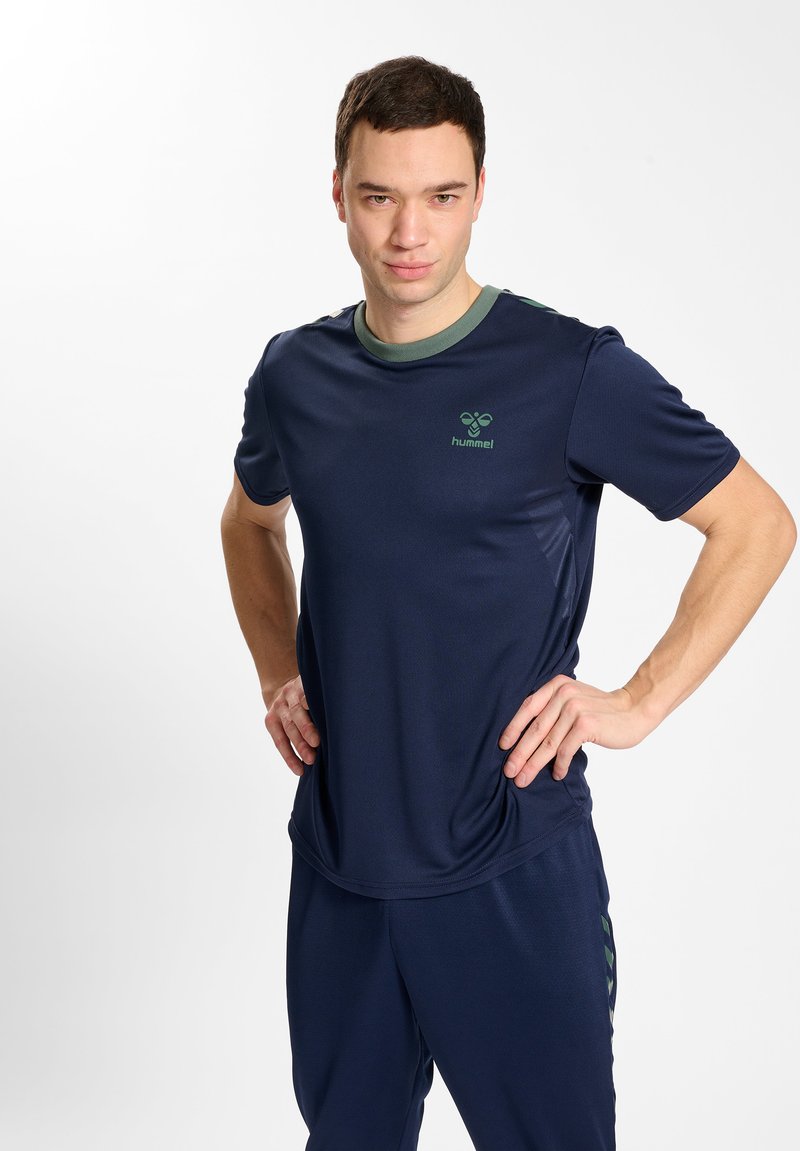 Marine sportshirt met een contrasterende groene kraag, gemaakt van vochtafvoerende stof. Bevat het "hummel" logo in het groen op de borst.
