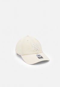 Beige Baseballcap aus Baumwolle, mit einem erhabenen weißen Logo, genähten Belüftungsösen und einem verstellbaren Riemen auf der Rückseite.