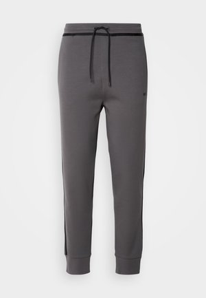 Grey sweatpants with a drawstring waist, side stripes, elastic cuffs, and smooth texture, featuring minimalistic design and no visible pockets.