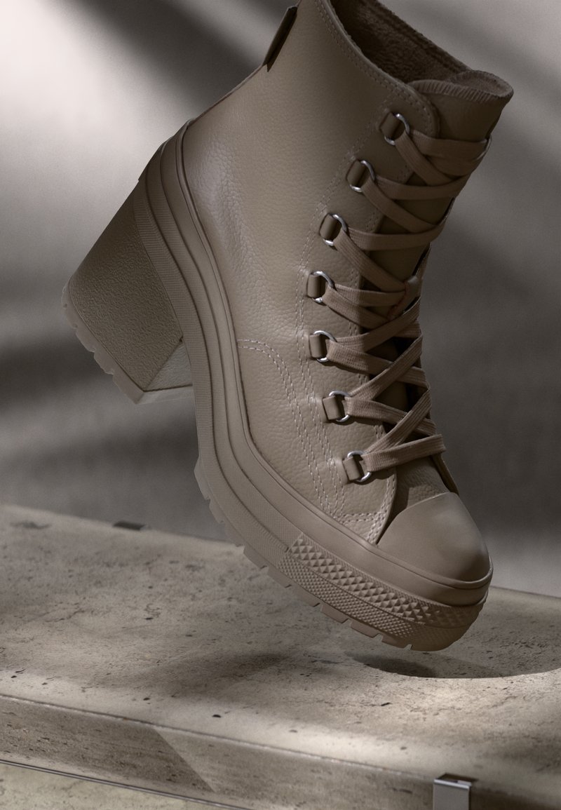 Beige leather ankle boot with a chunky heel, lace-up design, textured upper, and rubber sole featuring a patterned trim.