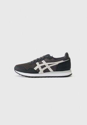 Black athletic sneakers made of mesh and suede, featuring white accents and a textured sole, with a rounded toe and lace-up design.