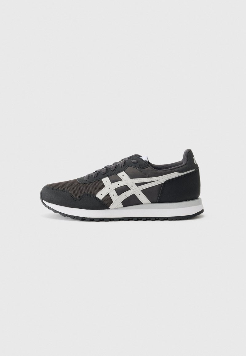 Baskets de sport noires en mesh et en daim, avec des accents blancs et une semelle texturée, dotées d'un bout arrondi et d'un design à lacets.
