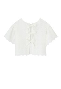 Blouse blanche cropped avec des bords en forme de vagues, un motif œillet et des détails en ruban noué à l'arrière. De courtes manches volantes complètent le design.