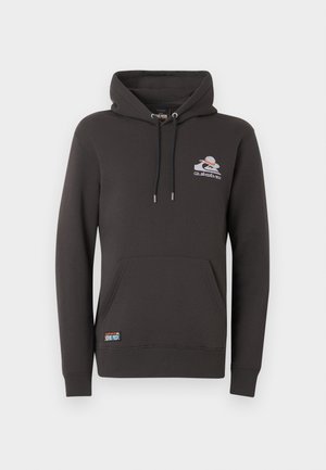 Sudadera negra con capucha, bolsillo tipo canguro en la parte frontal, cordones ajustables y pequeño logo blanco y naranja en el lado izquierdo del pecho, además de una etiqueta cerca del dobladillo inferior.