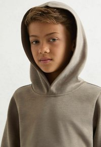 Hætte sweatshirt i lys brun, lavet af blødt stof. Har en afslappet pasform, sømløs halsudskæring og et enkelt design uden synlige mønstre.