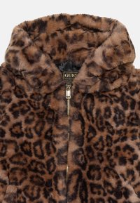 Veste en faux fourrure à imprimé léopard marron et noir avec capuche et zip doré, montrant l'étiquette à l'intérieur du col.