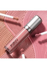 Roze getinte KIKO Milano vloeibare lippenstift met zilverkleurige dop, liggend op gestructureerde wervelingen van roze en nude lipgloss, omringd door drie applicators.
