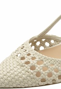 Sandalo in pelle beige tessuta con design aperto, punta chiusa e cinturino alla caviglia. Presenta intricate trecce e motivi ritagliati.