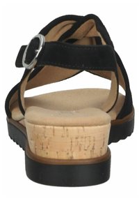 Sandale en suède noir avec une plateforme en liège et un léger talon surélevé. Sangle ajustable avec une boucle en argent, doublure intérieure douce.