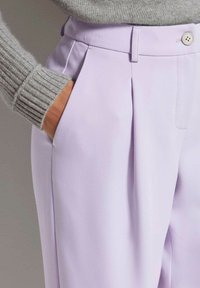 Light purple tailored trousers with pleats and side pockets. Made of smooth fabric, featuring a button closure at the waistband.