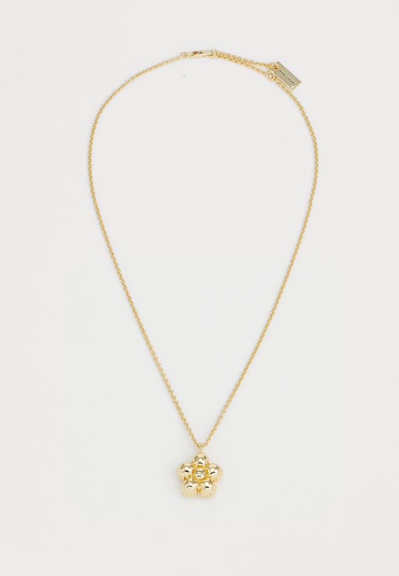Colar de ouro com um pendente floral de design texturizado, suspenso por uma corrente delicada. O fecho possui uma pequena etiqueta.