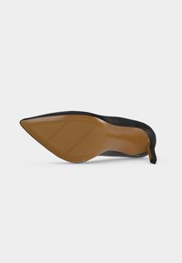 Chaussure noire à talon haut et bout pointu montrée par la semelle avec une semelle texturée marron et un talon aiguille fin sur fond blanc.