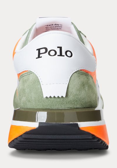 Aizmugures skats uz Polo sporta apavu ar baltu ādu, zaļu velūru, oranžām detaļām un melnu gumijas zolīti.