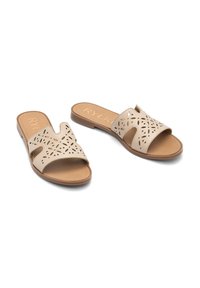 Beżowe sandały wsuwane zrobione ze skóry, z wyciętymi wzorami kwiatowymi, posiadające wyściełaną wkładkę i gładką powierzchnię podeszwy.