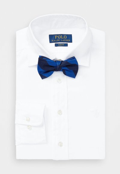 Camisa blanca entallada con puños de botón, que presenta un lazo con un patrón azul. Etiqueta "Polo Ralph Lauren" en el cuello. Textura de algodón suave.