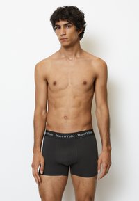 Boxer shorts neri in cotone con un morbido elastico in vita che presenta il nome del marchio "Marc O’Polo" in lettering bianco.