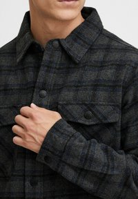 Geruite flanellen shirt in donkergrijs met blauwe accenten, met een knoopsluiting aan de voorkant en twee borstzakken. Gestructureerde stof en klassieke kraag.