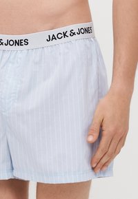 Boxers à rayures bleu clair avec une taille élastique arborant "JACK & JONES" en noir. Fabriqués à partir d'un tissu doux et léger.