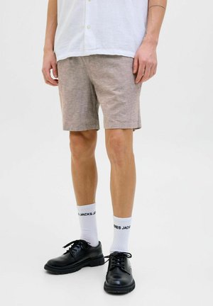 Light brown linen shorts with a classic cut, paired with black leather shoes and white socks featuring black text. Smooth texture, no patterns.