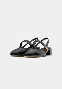 Black patent slingback shoes with a square toe, two adjustable straps, and a gold accent on the heel. Low block heel. Smooth texture.