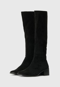 Botas negras hasta la rodilla hechas de suave ante, con puntera afilada y un tacón bloque para mayor estabilidad. Textura lisa con detalles de diseño mínimos.