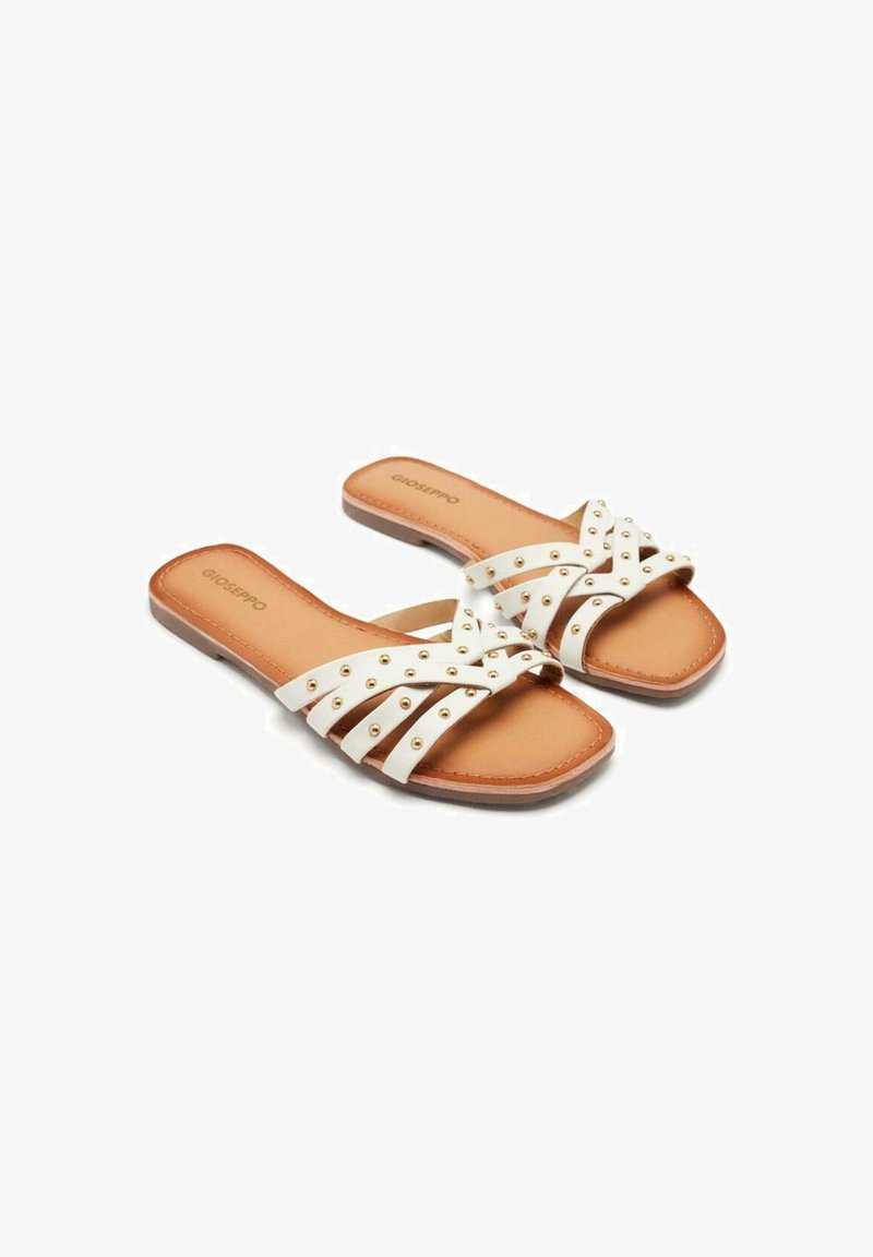 Sandales plates blanches avec plusieurs lanières croisées, ornées de clous dorés. Semelles intérieures et extérieure de couleur beige, avec un design à bout carré.