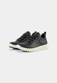 Czarne skórzane sneakersy z zaokrąglonym noskiem i teksturowanym wykończeniem; mają masywną białą podeszwę i czarne sznurowadła.