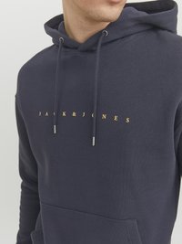 Mørkeblå hoodie lavet af blødt stof, med en forlommes, justerbare snore og guldtekst "JACK & JONES" tværs over brystet.