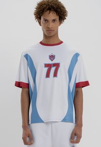 Balts īsām piedurknēm džersijs ar ziliem un sarkaniem akcentiem, ar lielu sarkanu "77" priekšpusē un logotipu virs tā. Mīksta, gluda auduma.