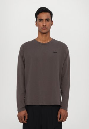 Koszulka z długim rękawem i okrągłym dekoltem w ciemnoszarym kolorze, uszyta z bawełnianej tkaniny, z dyskretnym czarnym logo na piersi i luźnym krojem.